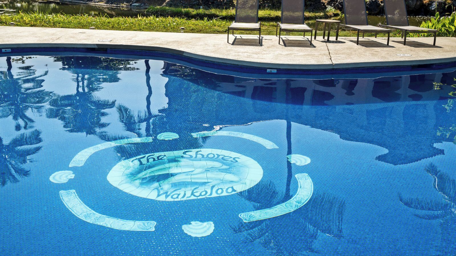 Una piscina con un diseño circular y las palabras "The Shores Waikoloa" escritas sobre el agua.