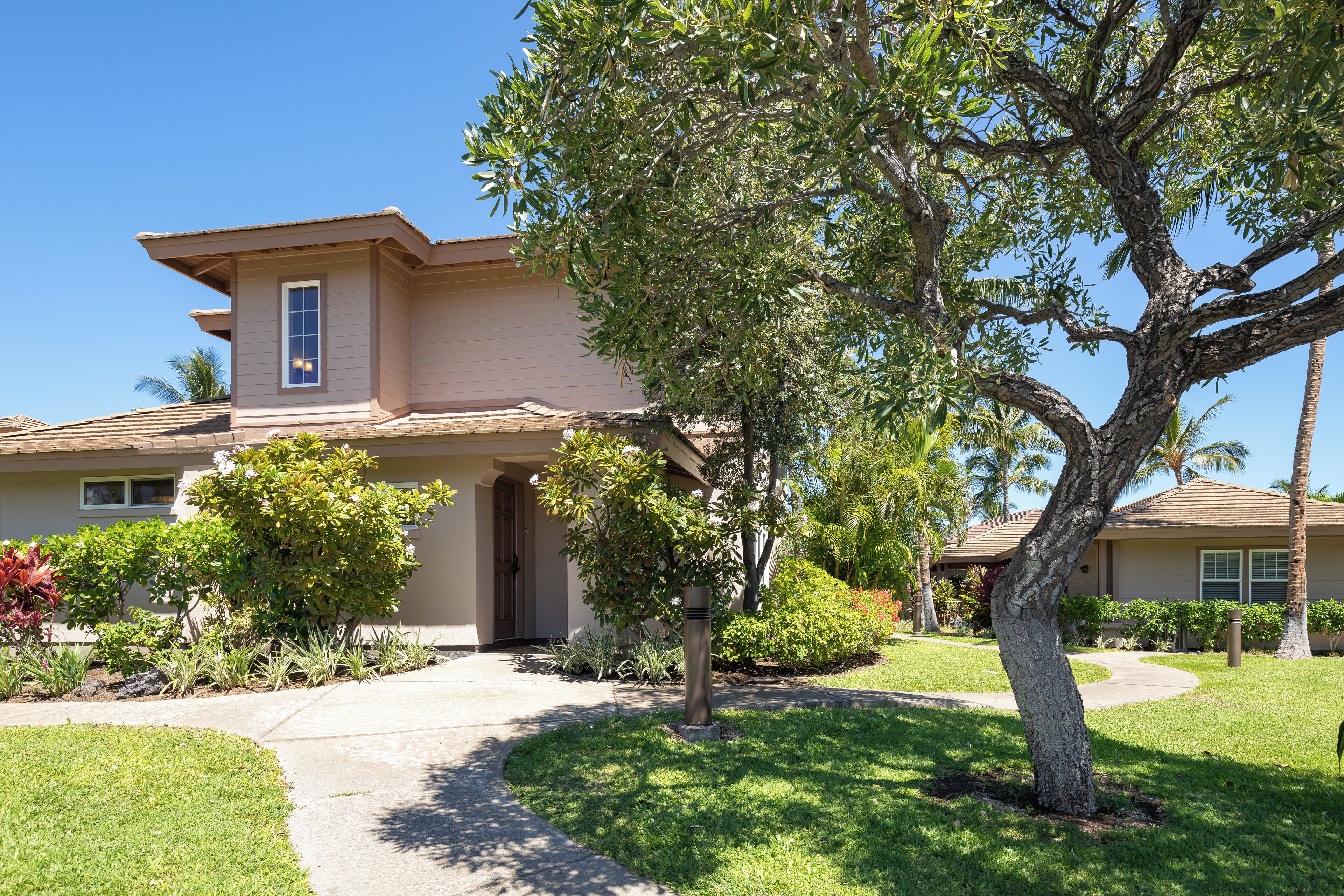 A two-story house with a front yard, a driveway, and a tree.
