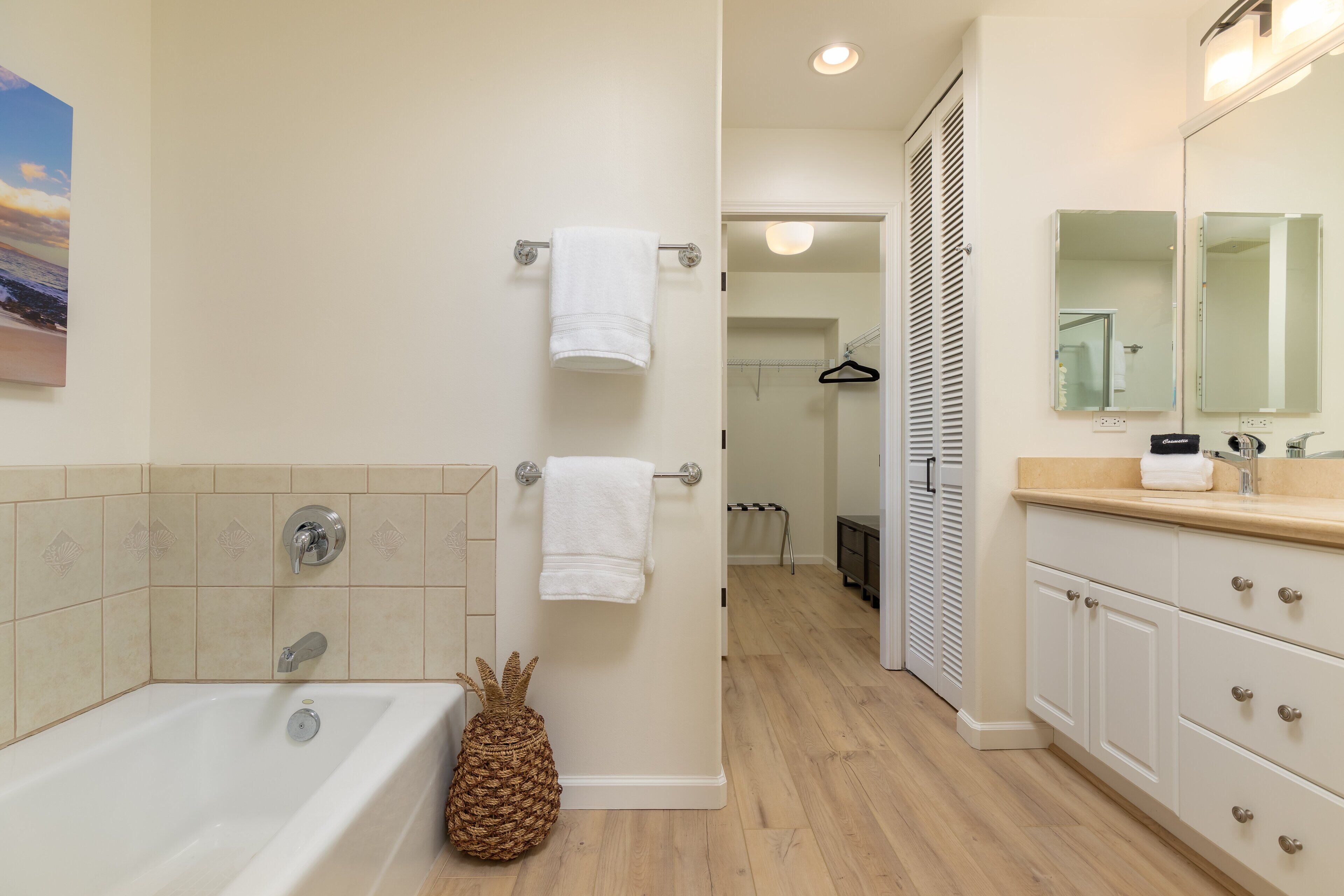 A modern bathroom with a bathtub, a large mirror, and a wooden floor.