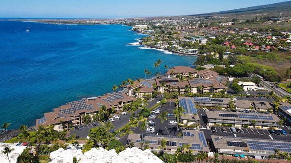 A coastal residential area with solar panel-equipped buildings, a marina, and a clear view of the ocean.