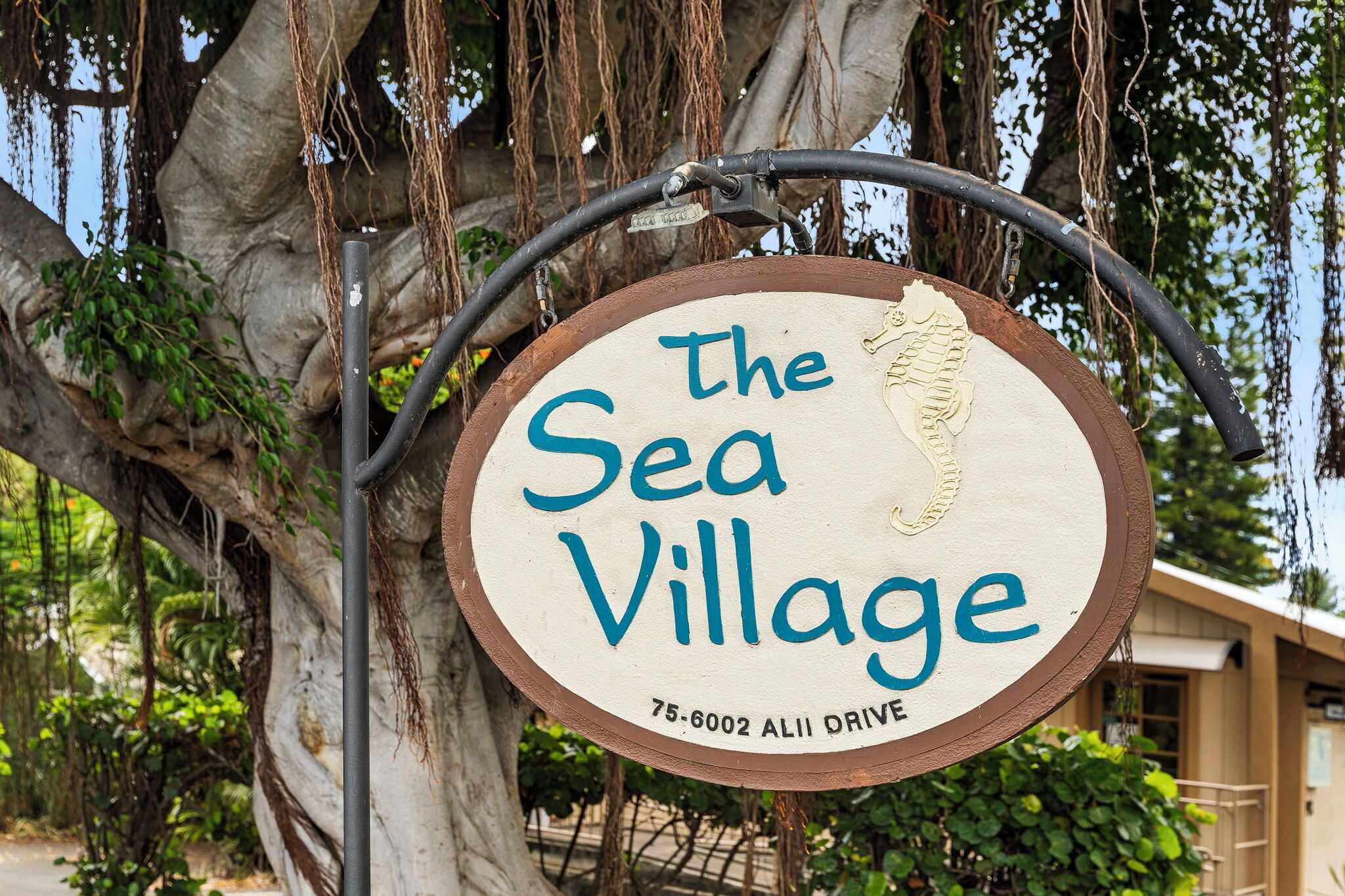 Un letrero que dice 'The Sea Village' con una playa al fondo.