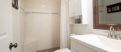 A bathroom with a shower, toilet, and sink.