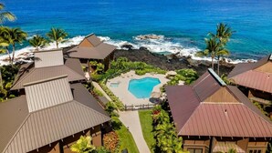 Un resort con piscina, vista al océano y jardines tropicales.