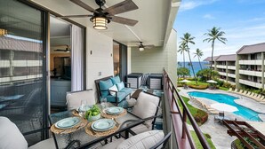 A balcony with a table set for dining, a sofa, and a ceiling fan. - Complete Remodel - Ocean & Mountain Views - Concierge - Walk to Magic Sands - Vrkcv (Kailua-Kona)