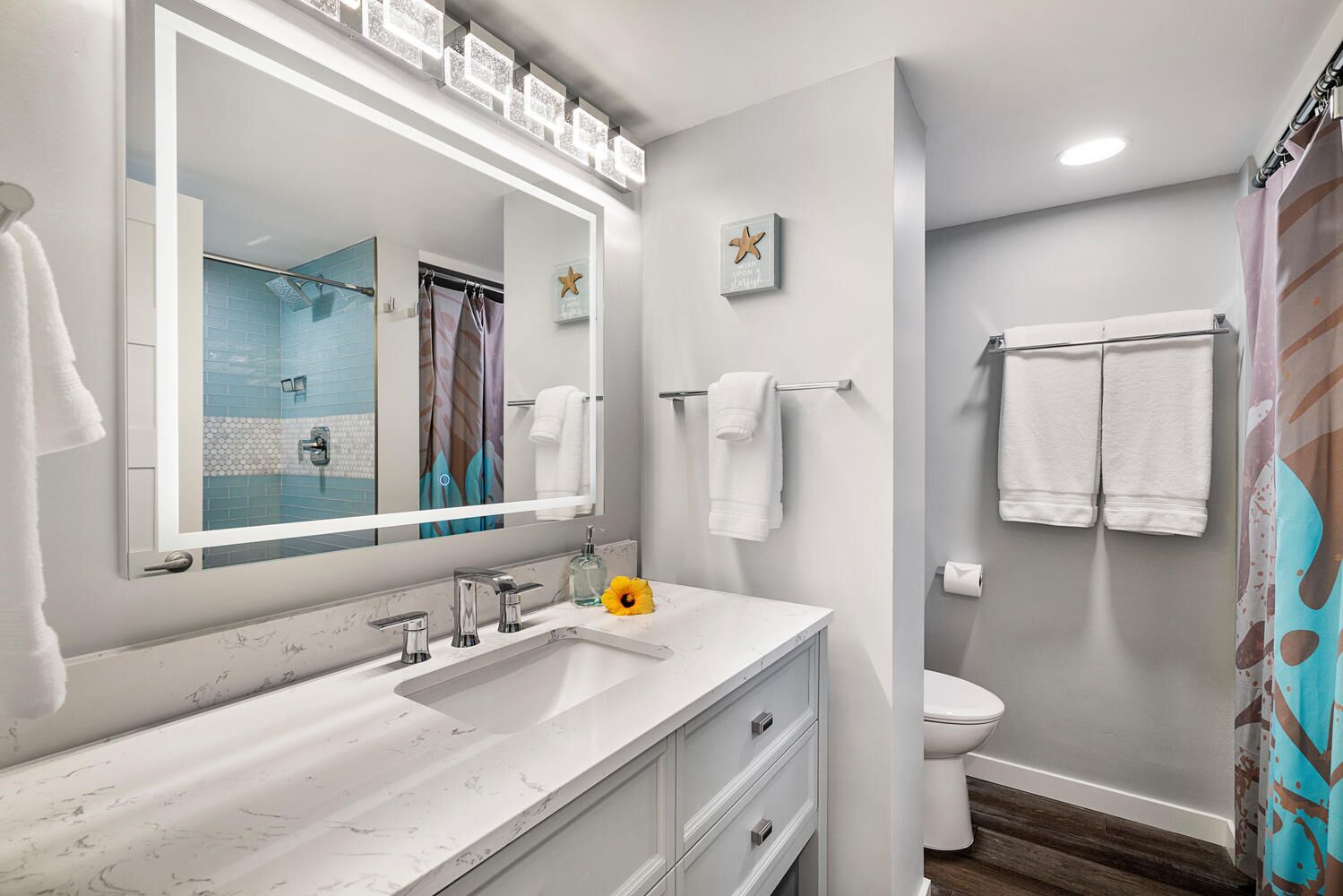 A modern bathroom with a large mirror, white vanity, and a shower area.