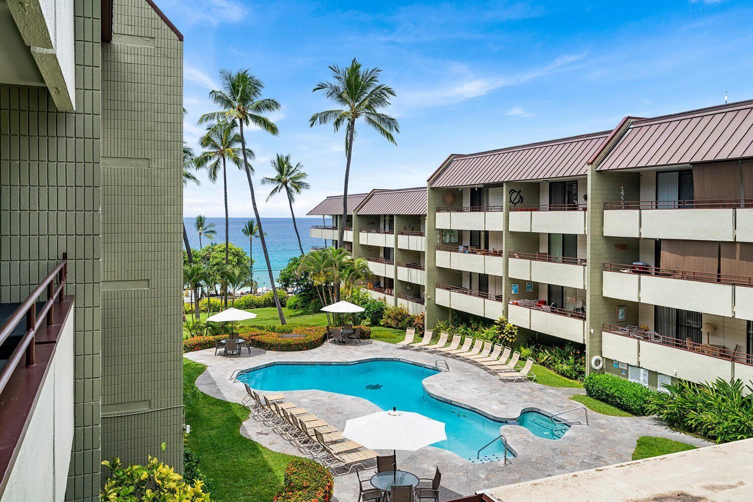 A hotel with a pool, palm trees, and a view of the ocean.