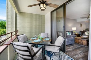 Un balcon avec une table dressée pour les repas, un canapé et un ventilateur de plafond.