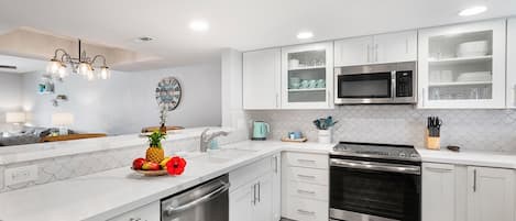 A modern kitchen with white cabinets, stainless steel appliances, a dishwasher, and a microwave.