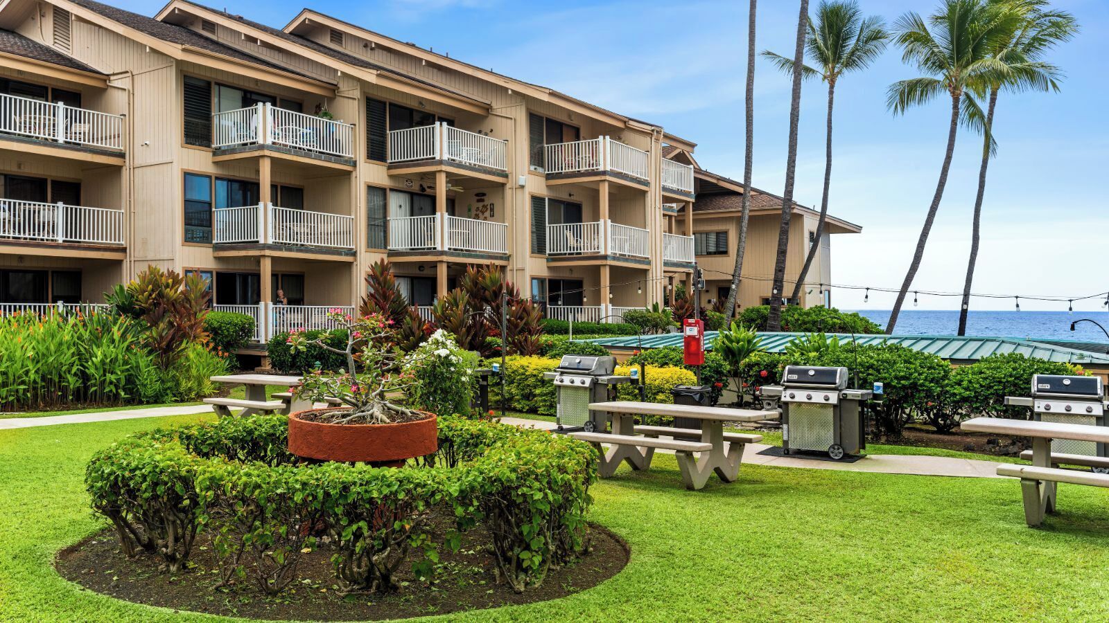 A multi-story hotel with balconies, outdoor seating, and a view of the ocean.
