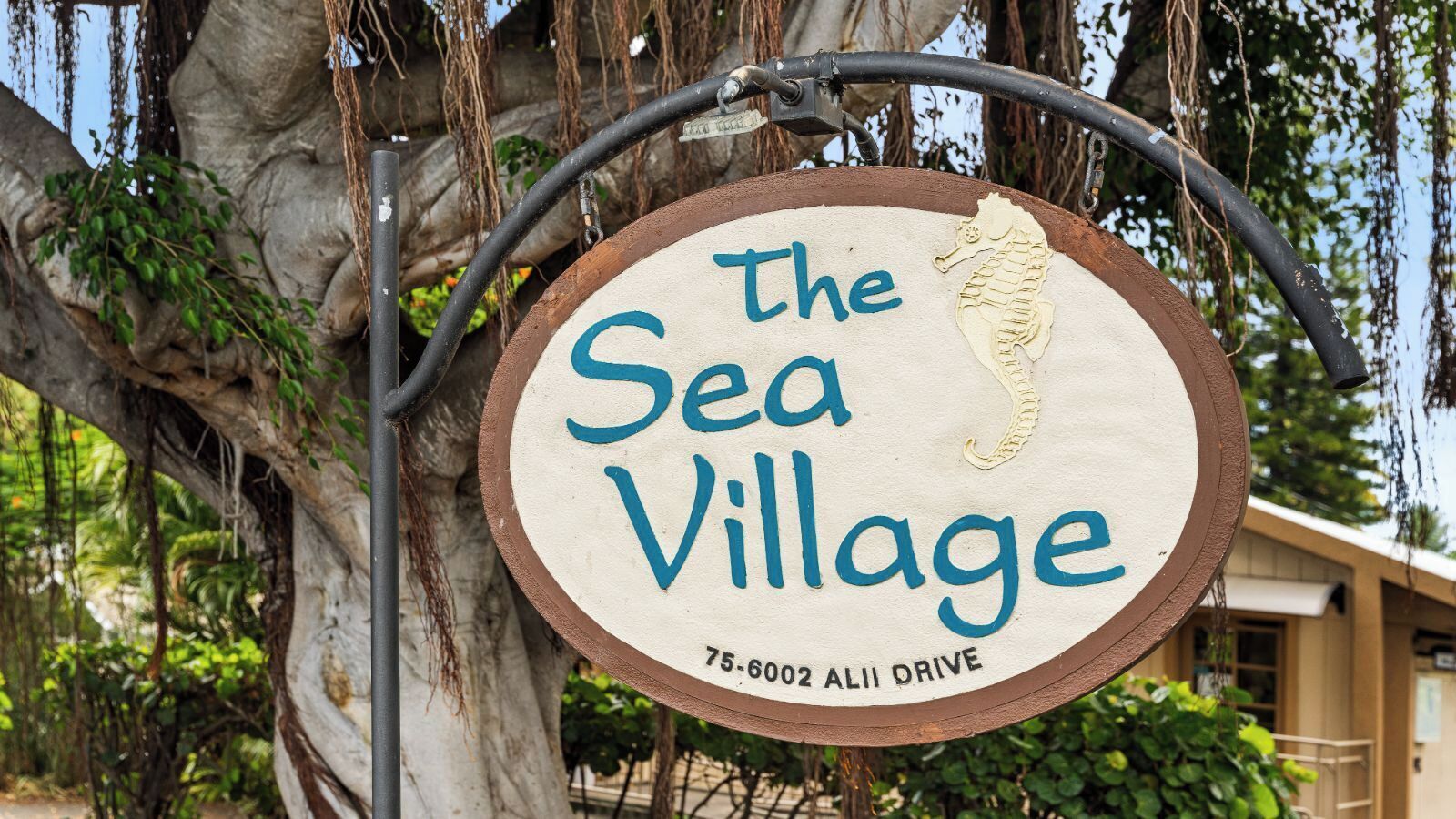 A sign for "The Sea Village" with a seahorse graphic, located at 75-6002 Alii Drive.