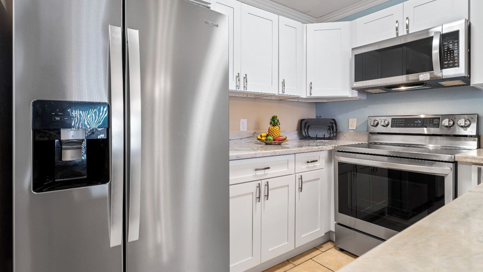 Una cocina moderna con electrodomésticos de acero inoxidable, armarios blancos y un dispensador de agua integrado.