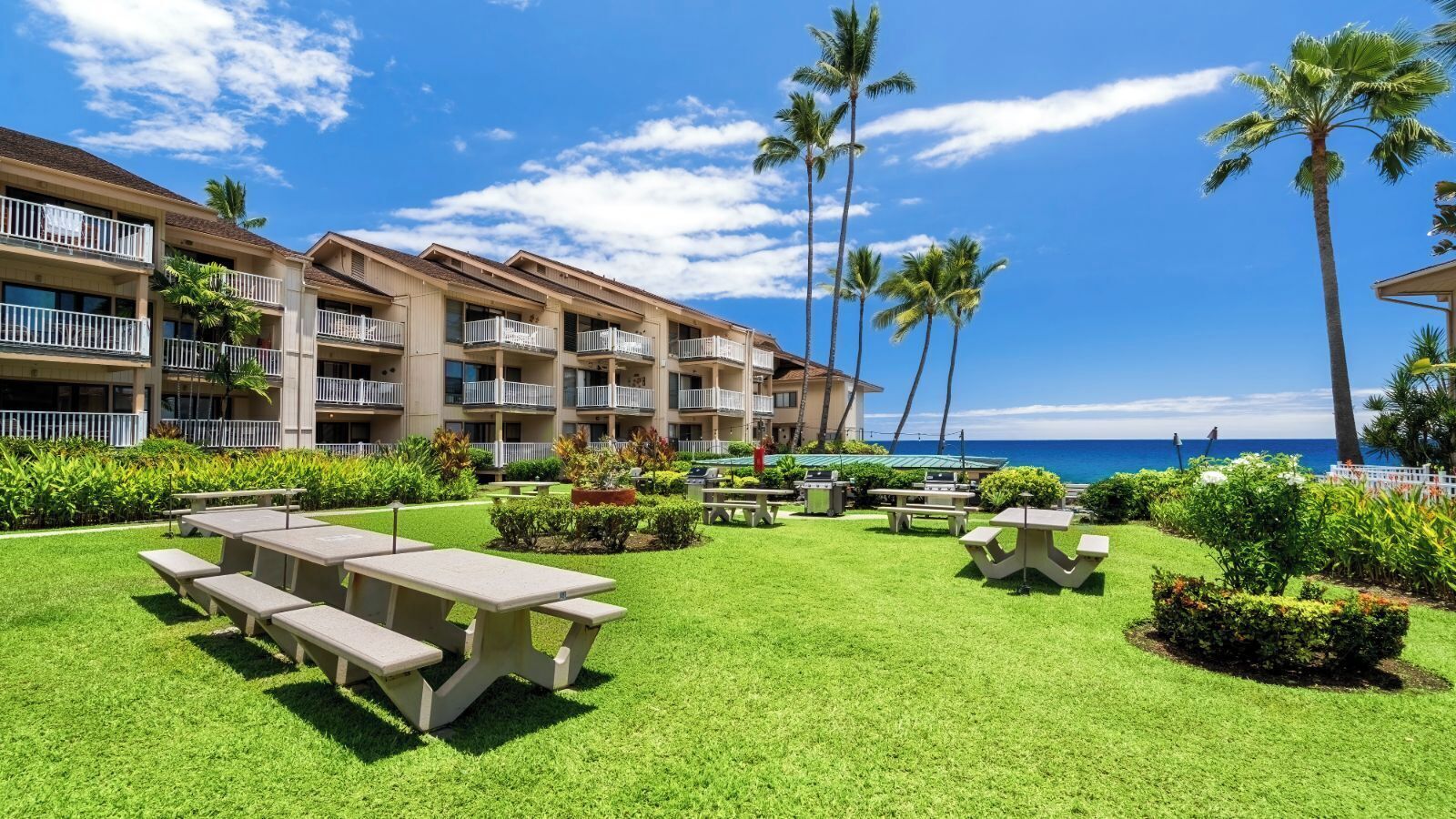 A hotel with a pool area, outdoor seating, and a view of the ocean.