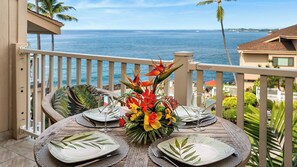 Mesa para dos con un centro de mesa floral tropical, con vistas a la costa.