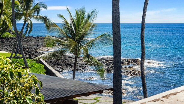 A beach view with palm trees, a wooden deck, and a rocky shoreline. - Ocean View Unit w Lanai - AC - Near Marketplace! - Vrkcv (Kailua-Kona)