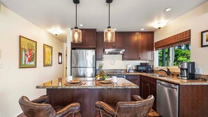 A modern kitchen with a central island, stainless steel appliances, and bar stools. - Ocean View Unit w Lanai - AC - Near Marketplace! - Vrkcv (Kailua-Kona)