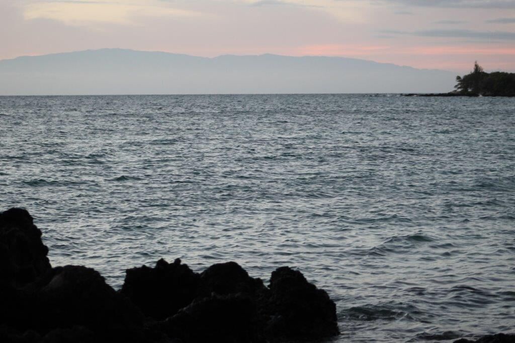 A coastal view with rocky terrain and distant mountains.