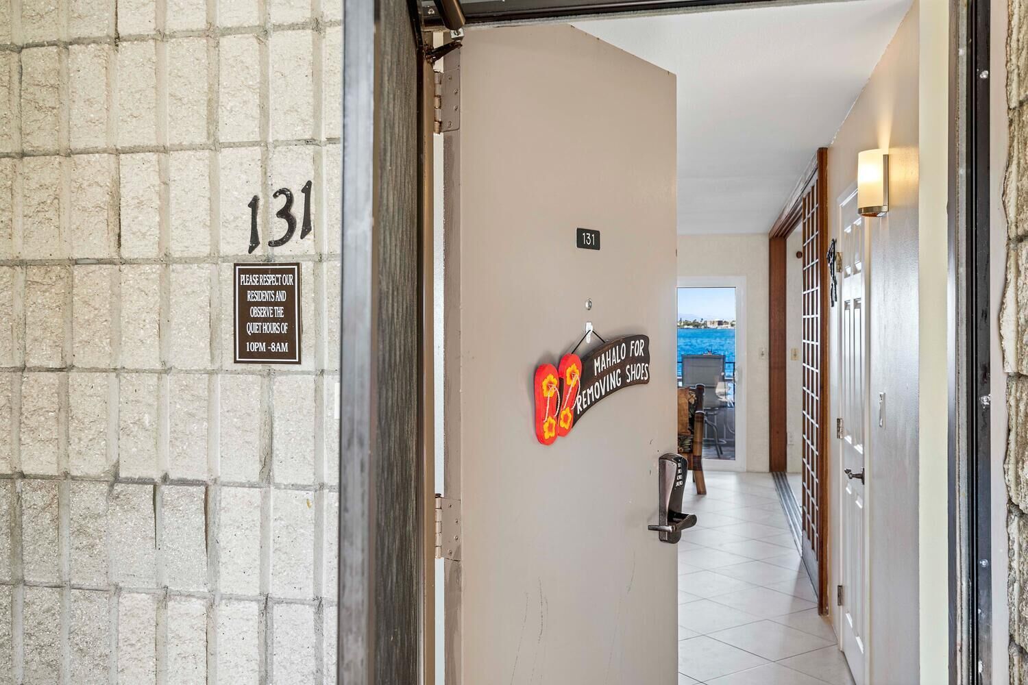 Un pasillo con un cartel que indica la habitación 131, una solicitud para respetar a los residentes y observar el horario de silencio de 22:00 a 8:00, y un cartel para quitarse los zapatos.