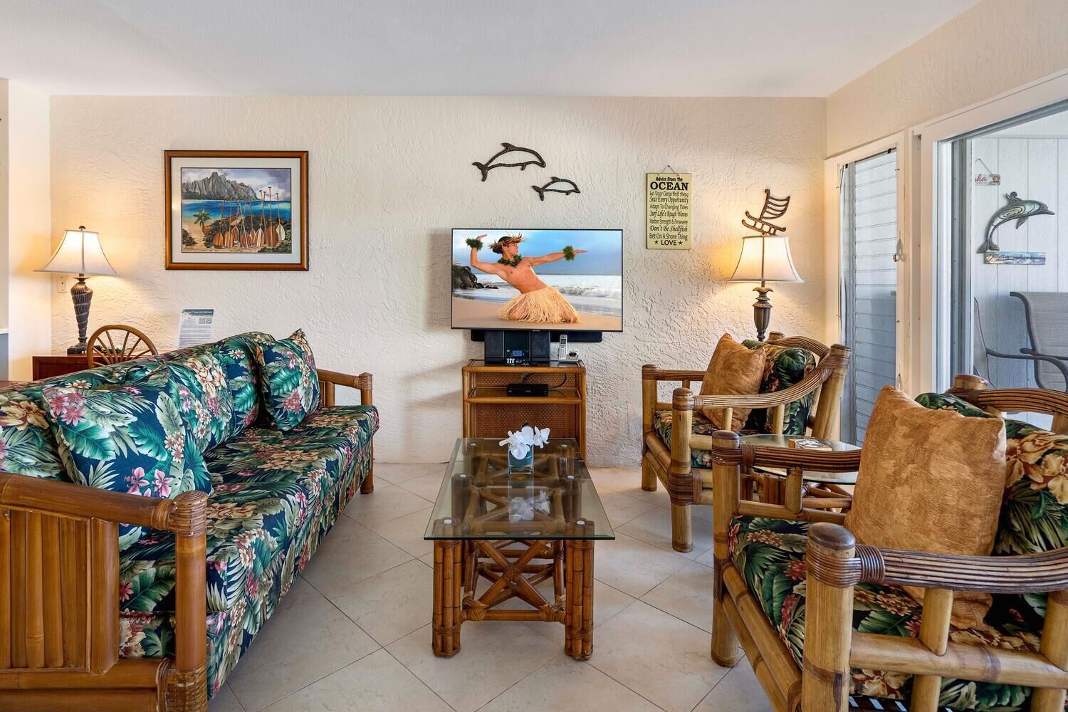 A living room with a sofa, chairs, a coffee table, a TV, and decorative wall art.