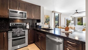 A modern kitchen with dark wood cabinets, stainless steel appliances, and a large island with a pineapple centerpiece.