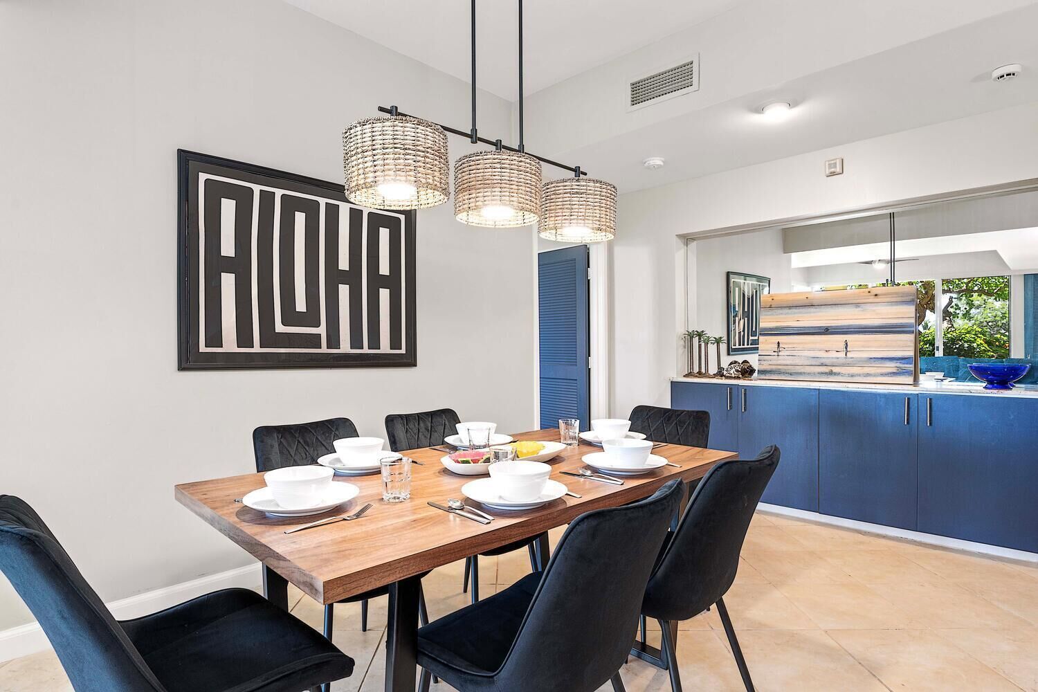 A modern dining area with a wooden table set for six, black chairs, and a large abstract artwork on the wall.
