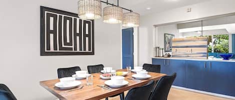 A modern dining area with a wooden table set for six, black chairs, and a large abstract artwork on the wall.
