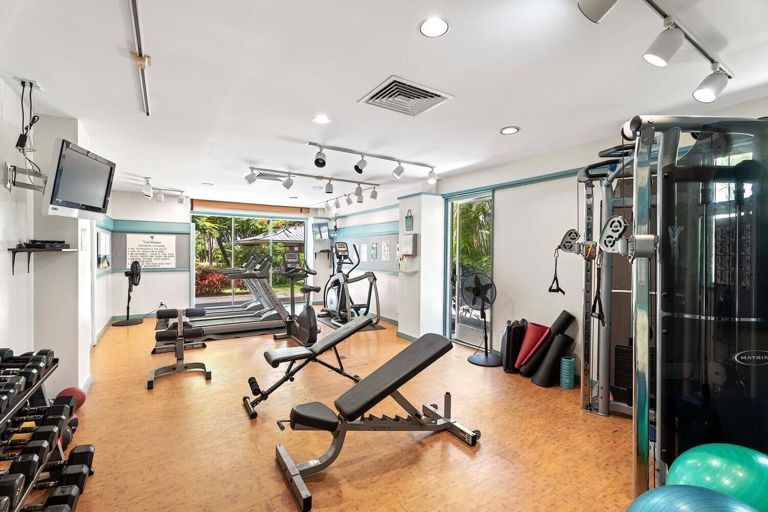 A gym with treadmills, elliptical machines, free weights, and a bench press.