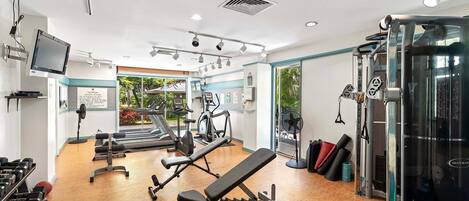 A gym with treadmills, elliptical machines, free weights, and a bench press.