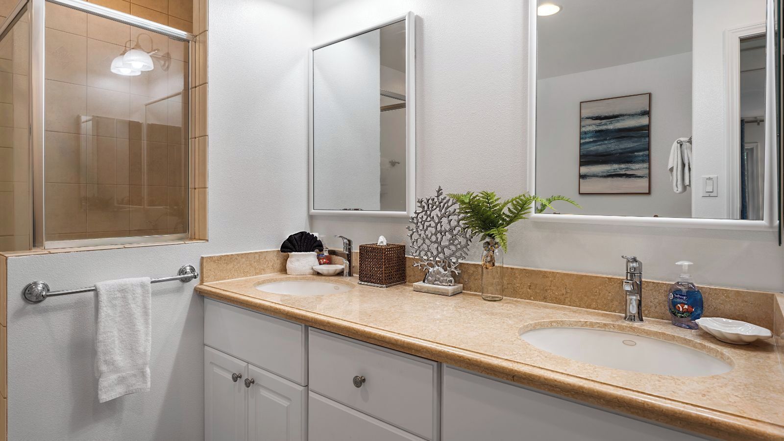 Un baño moderno con dos lavamanos, un espejo grande y un perchero para toallas.