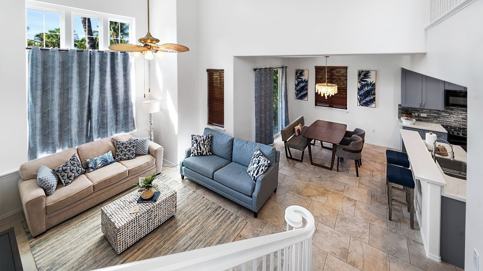 A spacious living area with a sofa, coffee table, and a dining table with chairs. There is a kitchen area with a countertop and sink.