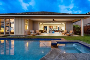A modern house with a swimming pool, outdoor seating area, and a well-lit interior. - Unbelievable Ocean Front View w Pool - AC - Outdoor Seating!- Vrkcv (Kailua-Kona)