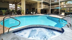 Una piscina con hidromasaje, sillas de descanso y una zona de estar techada.