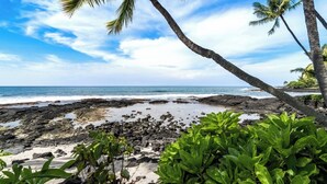 Una playa rocosa con palmeras y olas del océano.