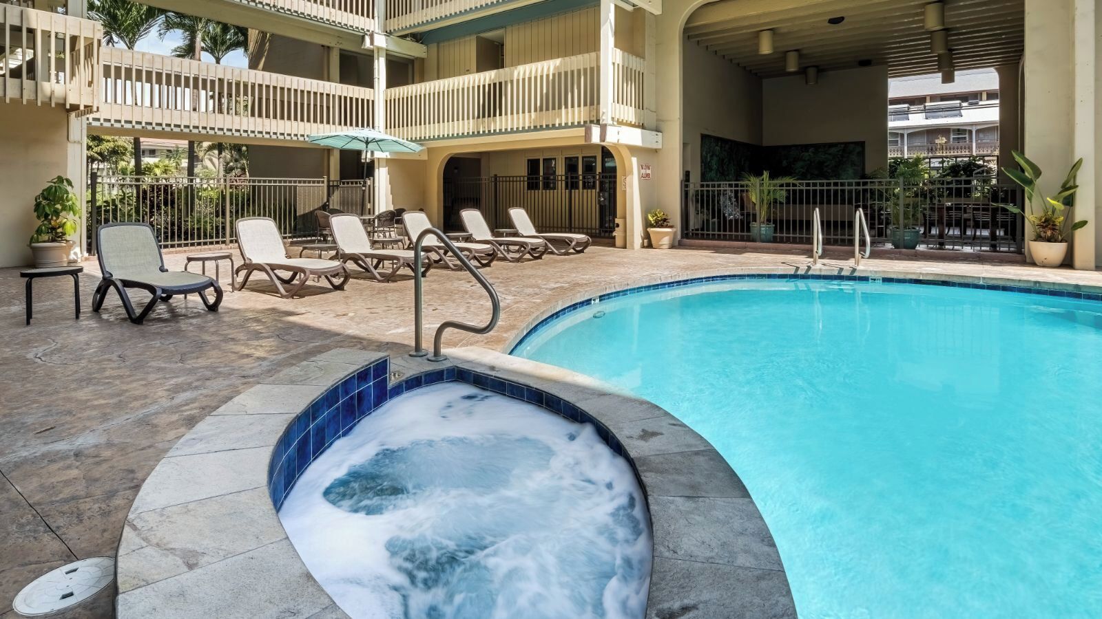 A swimming pool with lounge chairs and a hot tub area.