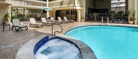 A swimming pool with lounge chairs and a hot tub area.