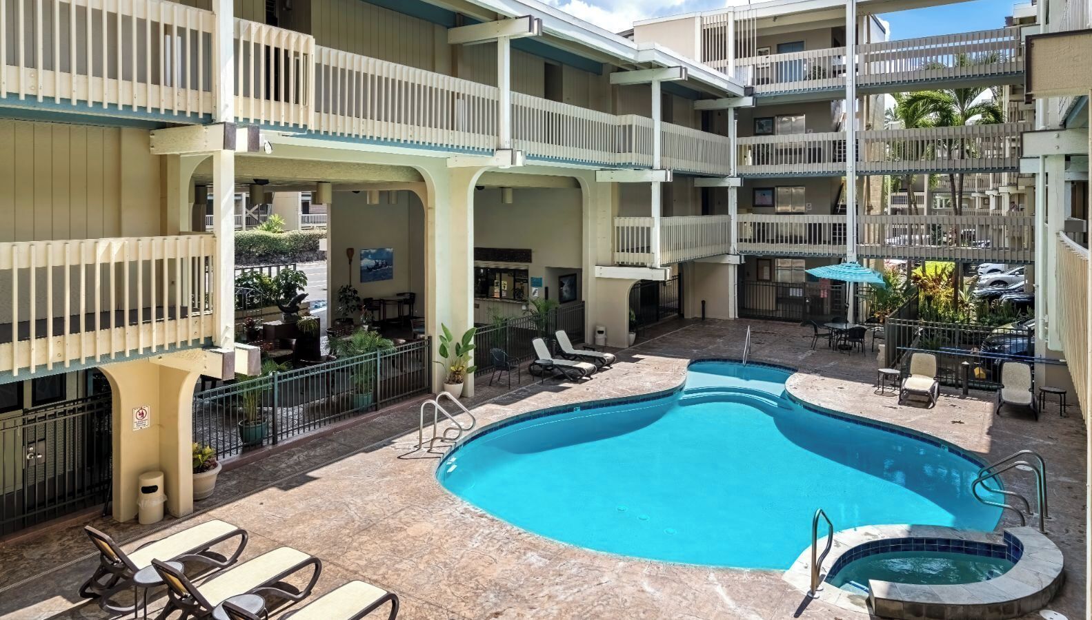 A hotel with a swimming pool, multiple balconies, and outdoor seating areas.