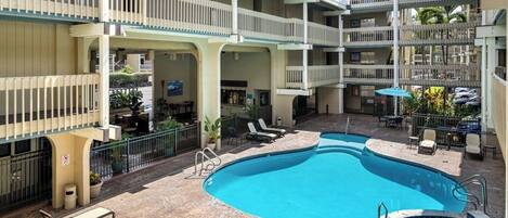 A hotel with a swimming pool, multiple balconies, and outdoor seating areas.