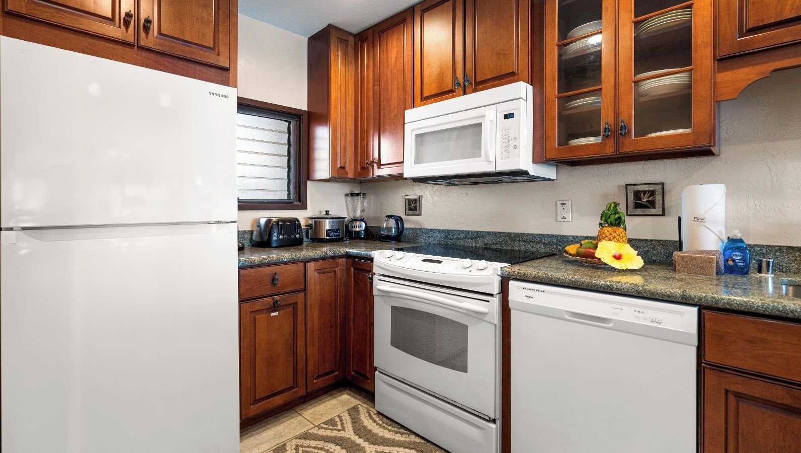 Una cocina con armarios de madera, un refrigerador blanco, un microondas, una estufa y un lavavajillas.
