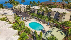 A resort with a swimming pool, palm trees, and a view of the ocean. - Ocean Front Condo - Vrkcv (Kailua-Kona)