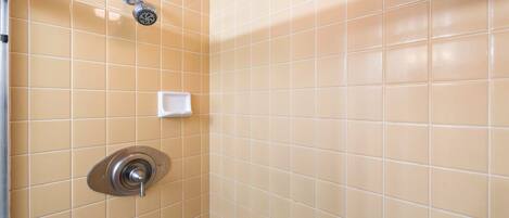 A bathroom with beige tiles, a showerhead, and a soap dish.