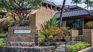 Un bâtiment sur lequel on peut lire l’inscription « KONA PACIFIC », ainsi qu’un mur de pierre avec des marches menant à l’entrée.