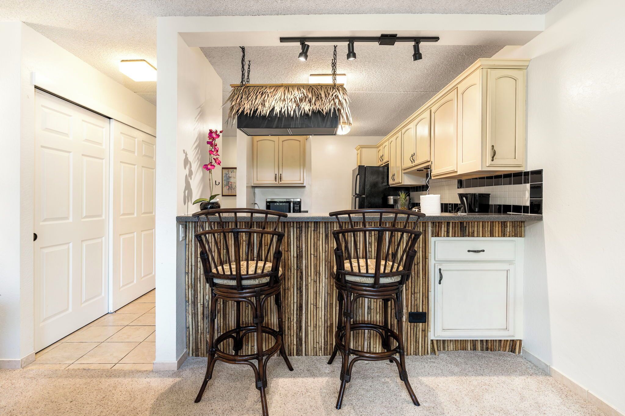 A kitchen with two bar stools, a hanging light fixture, and a white door in the background.