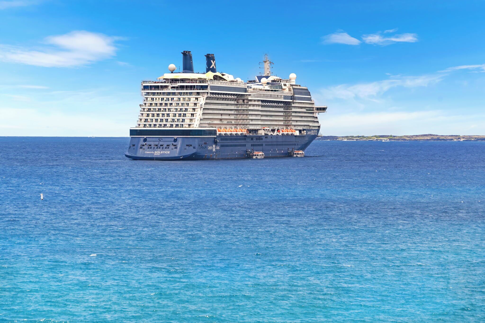 Un grand navire de croisière doté de nombreux ponts et balcons, voguant sur une mer calme.
