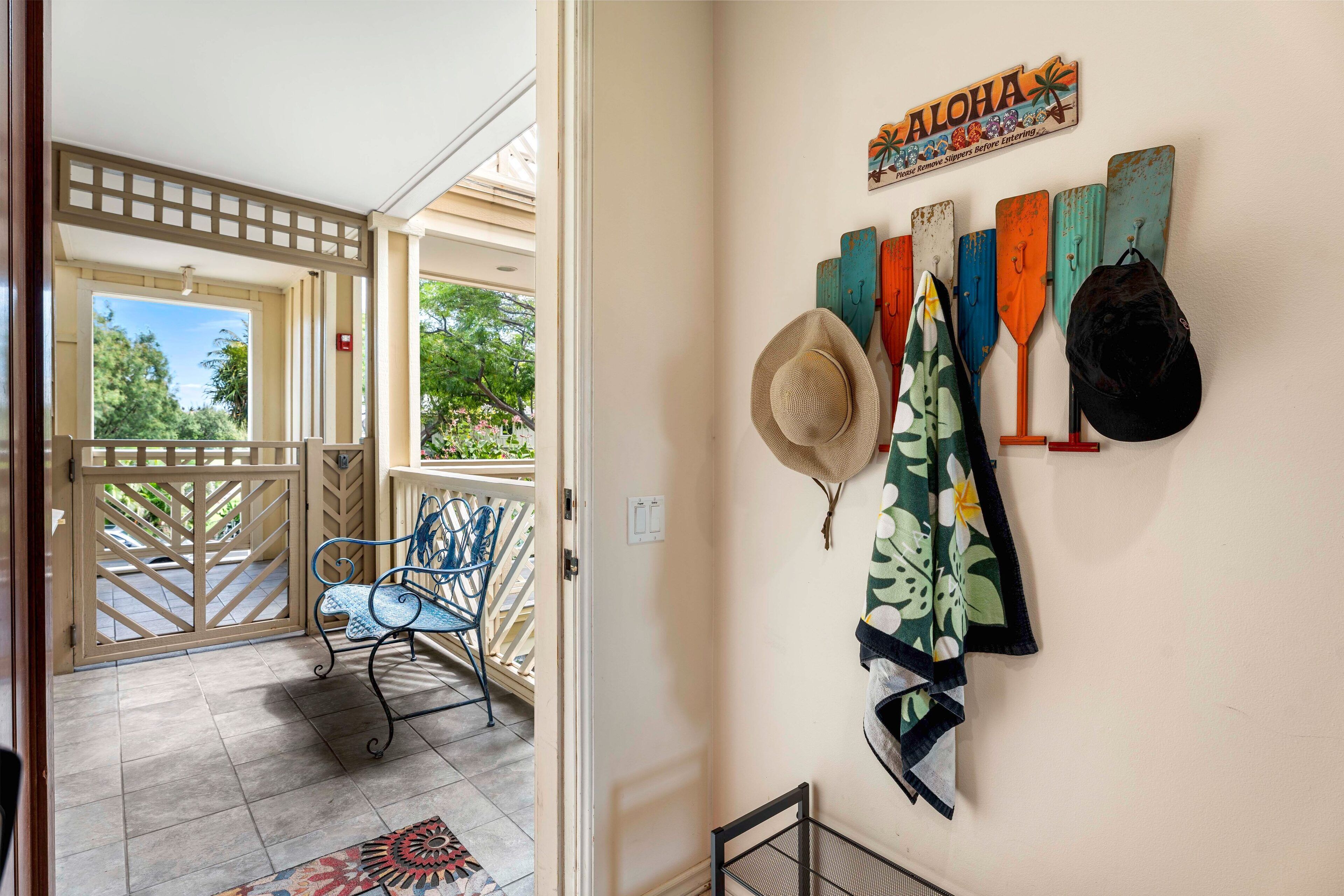 Una habitación con vista a un jardín a través de un ventanal, un perchero de pared y una pequeña estantería metálica.