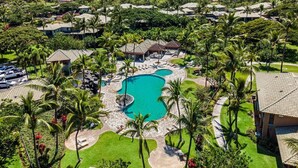 A resort with a central swimming pool surrounded by palm trees and a view of the ocean. - Luxurious View Corner Townhome - Great Views - VIP Beach Pass - Vrkcv (Kamuela)