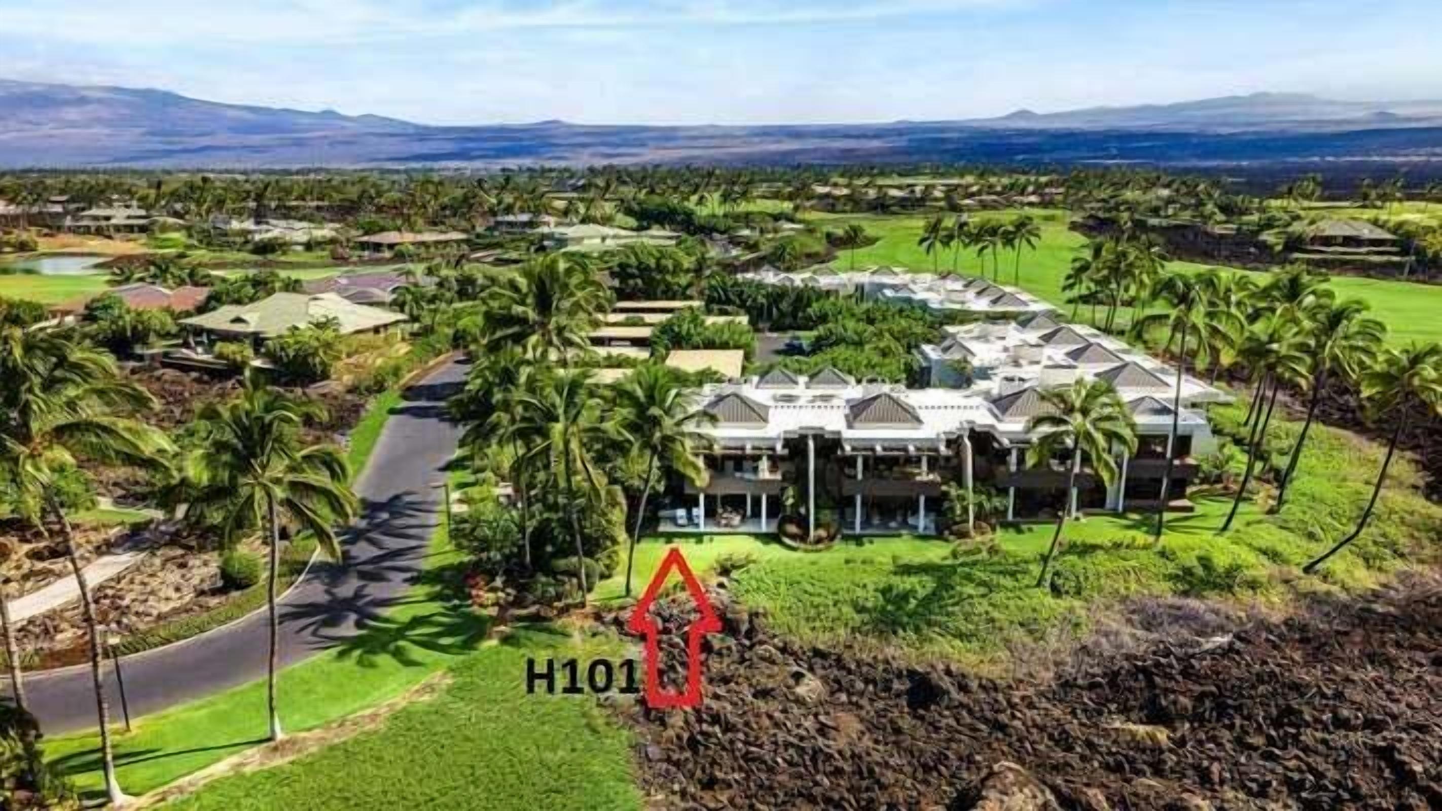 Un resort con un edificio grande, rodeado de palmeras y un campo de golf.