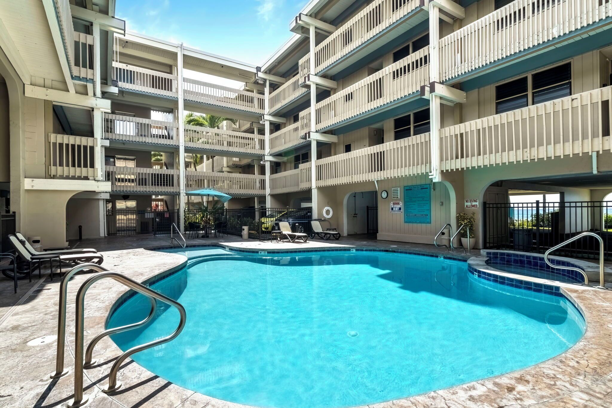 A multi-level hotel with a central swimming pool, outdoor seating, and balconies.
