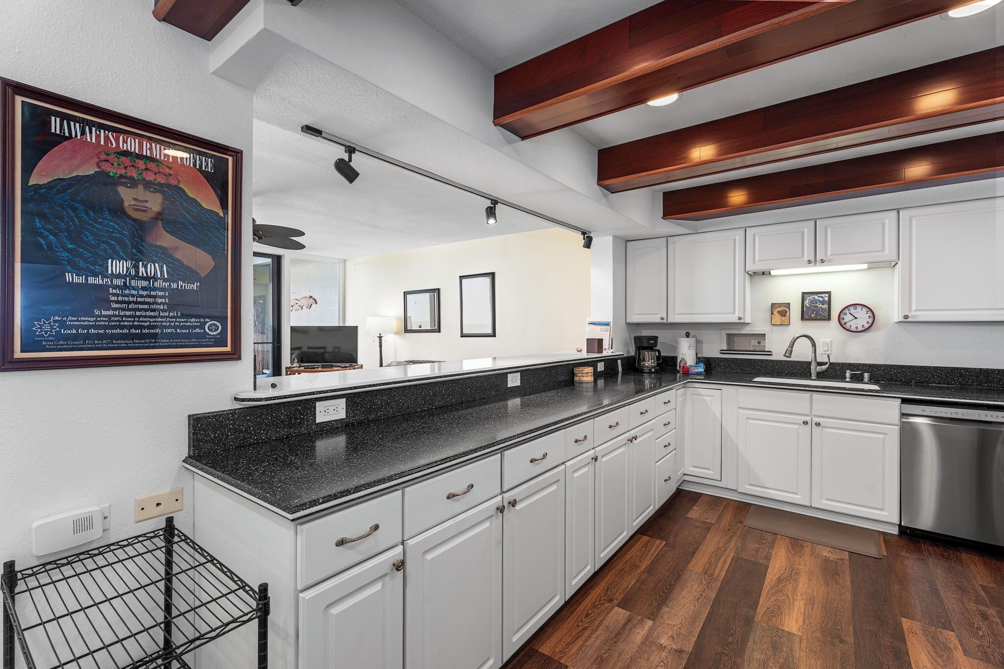 A modern kitchen with white cabinets, a black countertop, and a stainless steel dishwasher.