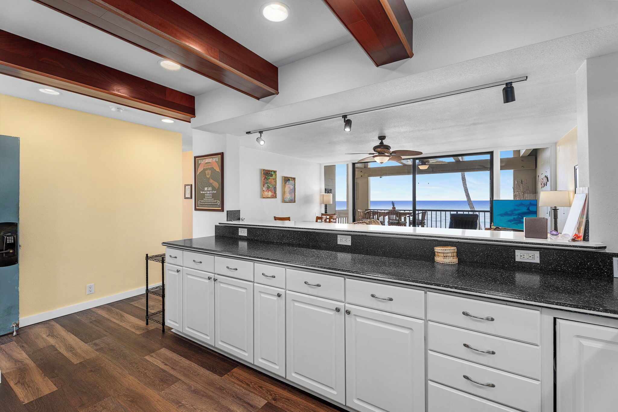 A modern kitchen with a large island, white cabinetry, and a view of the ocean.