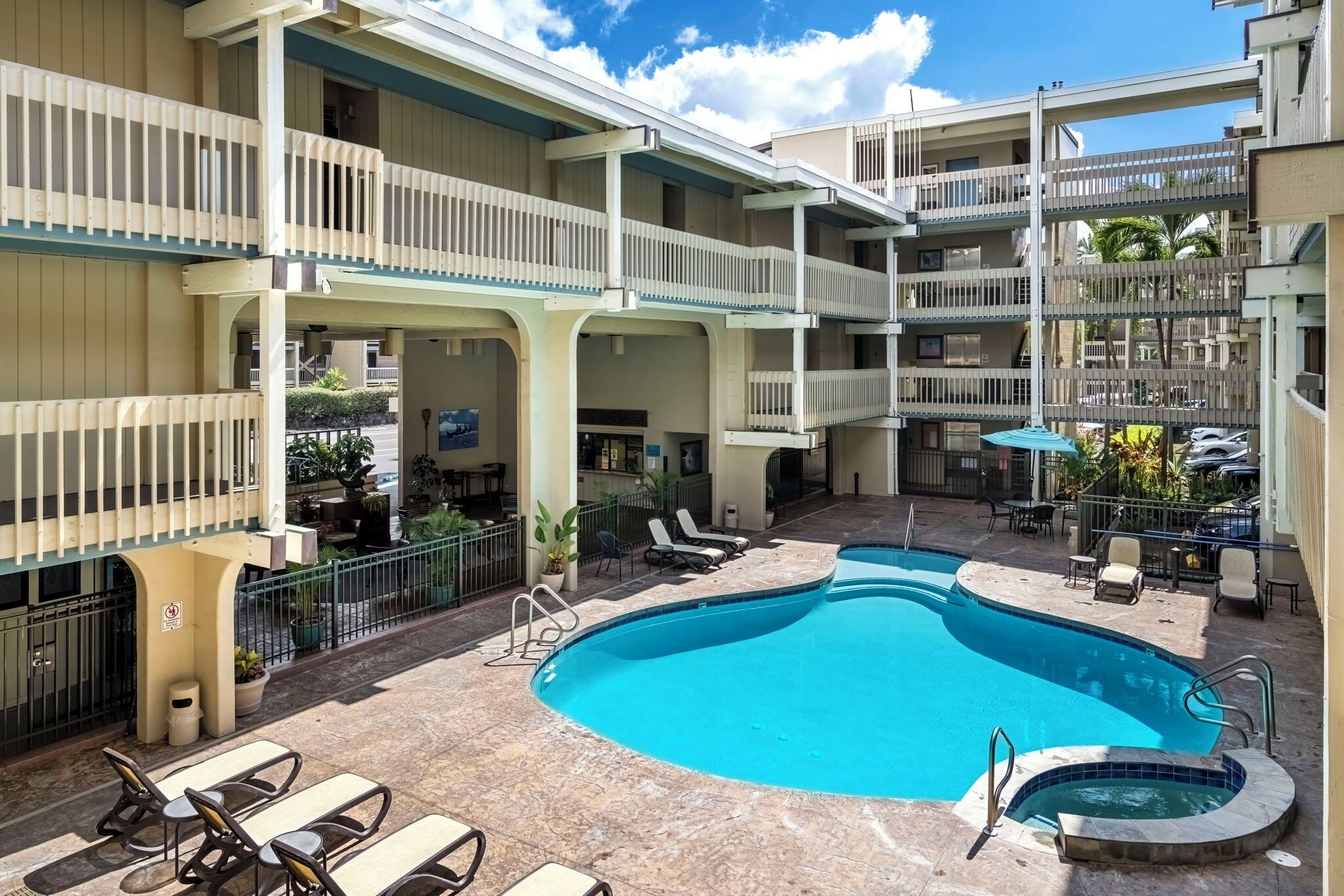 A multi-level hotel with a central swimming pool, outdoor seating, and balconies.