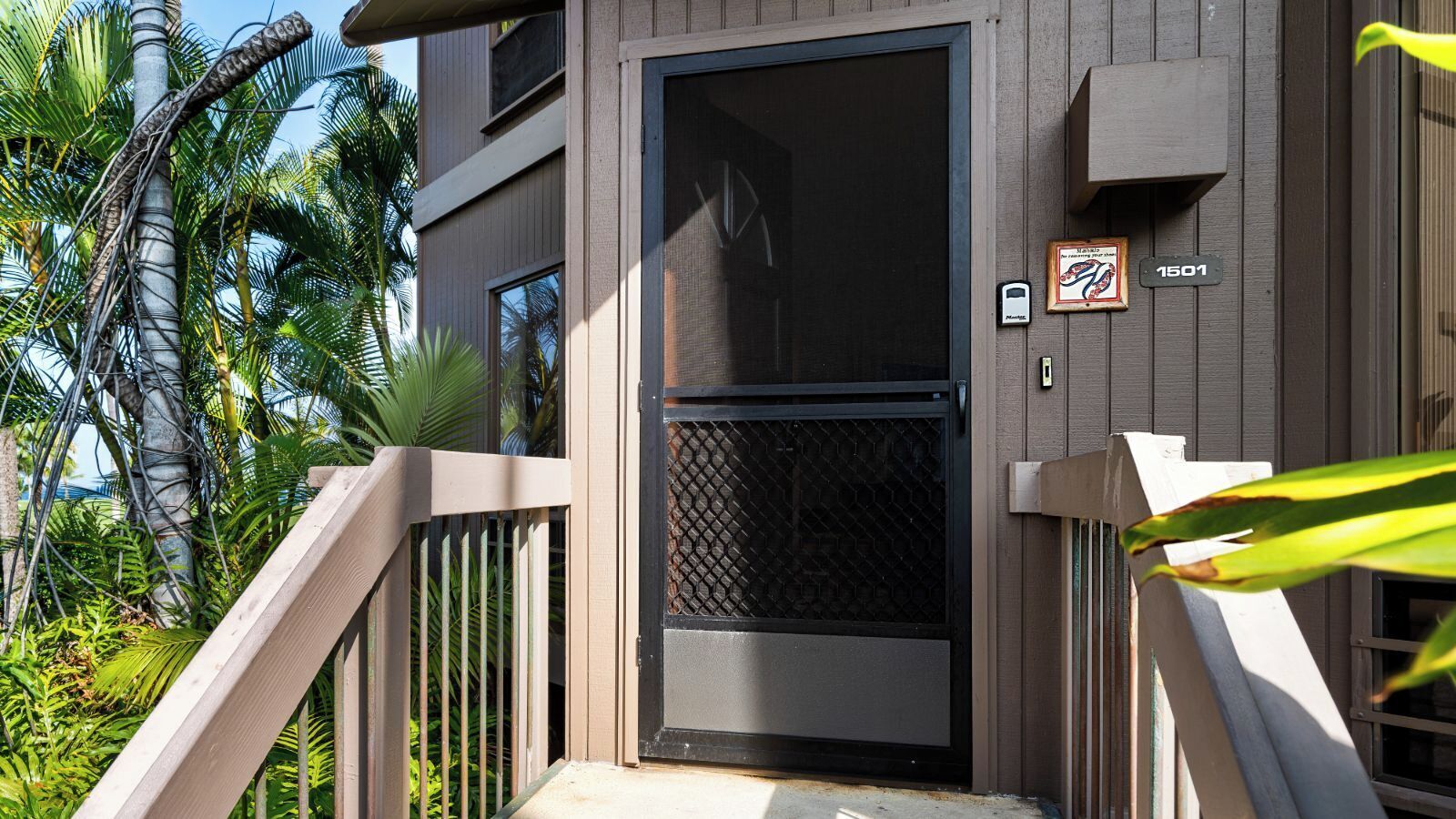 A modern building with a dark door, a security keypad, and a number sign '1501'.